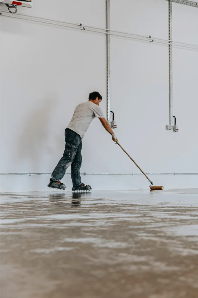Application d'une résine au rouleau sur le sol d'un local après travaux
