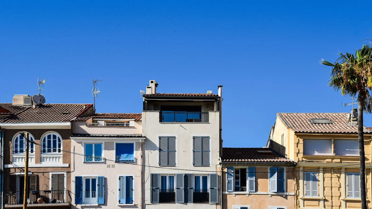 Façades en crépi clair avec volets bois et toitures en tuiles canal