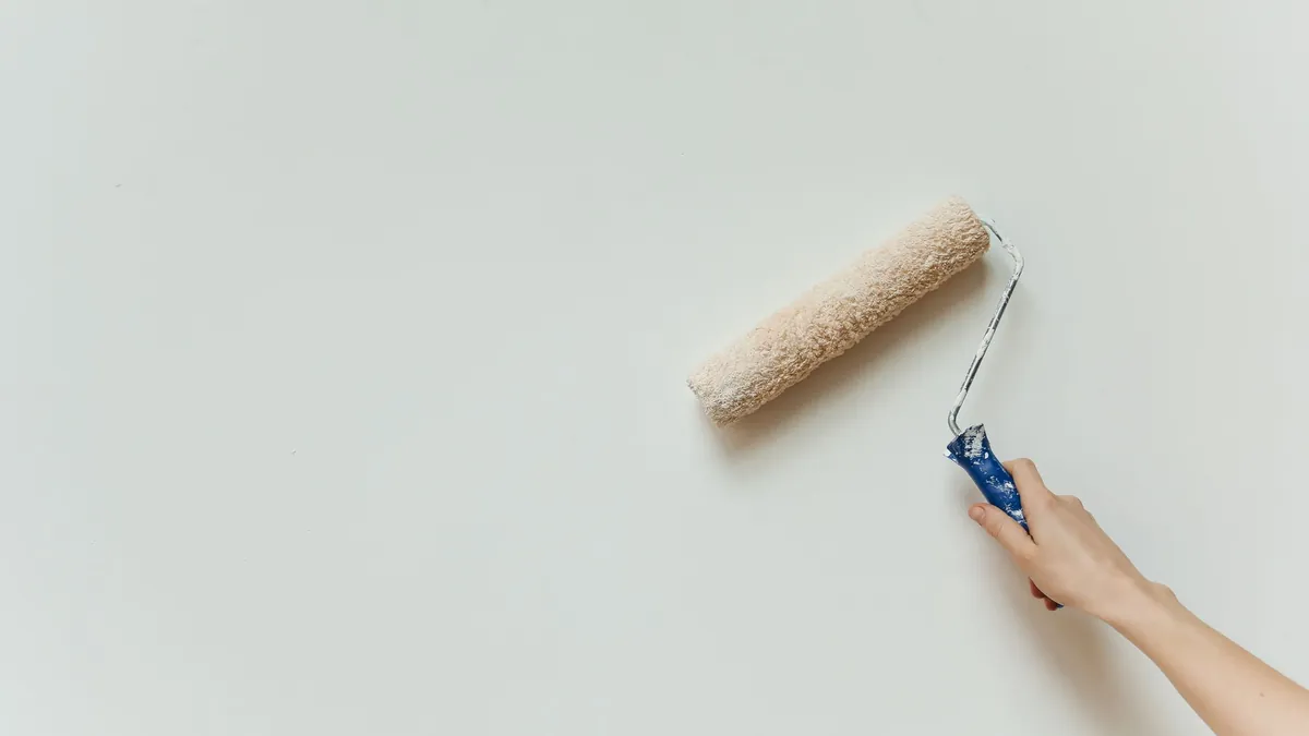 Rouleau appliquant une couche de peinture claire sur un mur