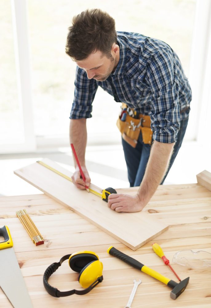 carpenter checking dimensions of wooden plank